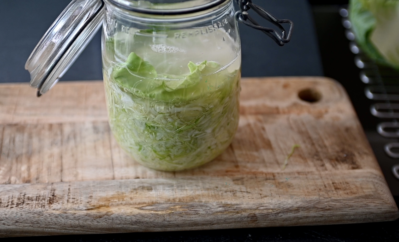 shredded green cabbage with salt brine in a glass jar